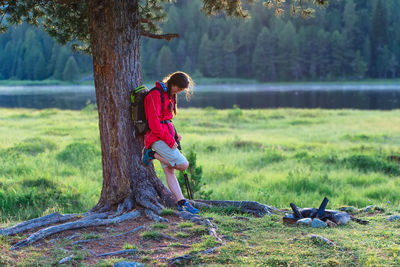 Full length of boy on tree trunk in field