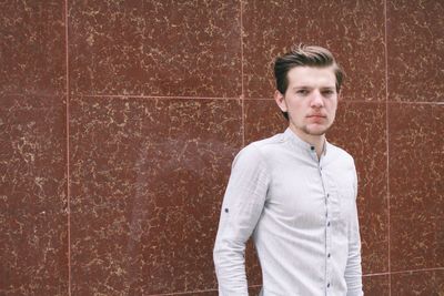 Front view of handsome man standing against wall