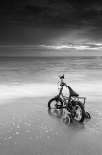 Man riding motorcycle on beach against sky