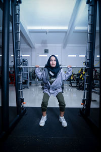 Full length of young woman exercising in gym