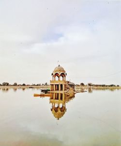 Traditional building by lake against sky