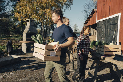 Mid adult man carrying crate full of vegetables at farmer's market