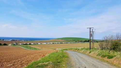 Road amidst field against sky