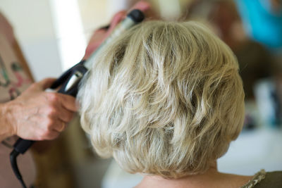 Cropped image of hairdresser styling customer hair in salon