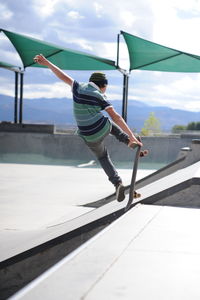 Boy skateboarding at park against sky