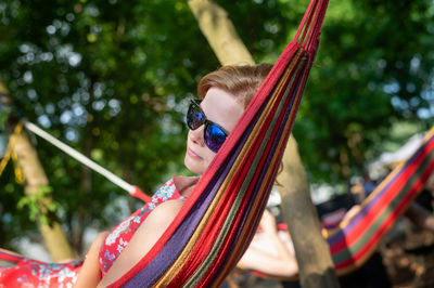 Outdoor portrait of woman enjoy in hammock outdoor. relaxing in the hammock in the summer garden