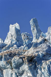 Low angle view of snow against clear blue sky