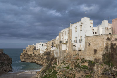 Buildings by sea against sky