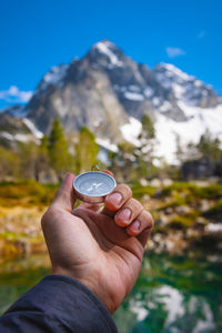 Man with a compass in his hand in the high mountains near a clear lake. travel concept. landscape