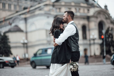Rear view of couple standing on street in city