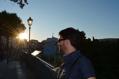 Young man in city against sky during sunset