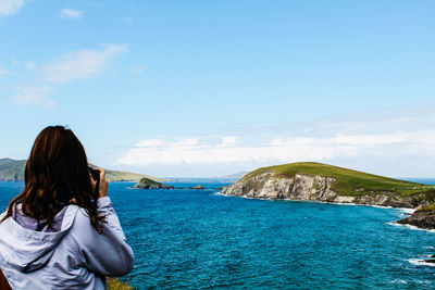 Rear view of woman looking at sea against sky