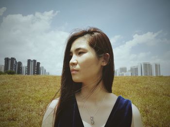Young woman looking at cityscape against sky
