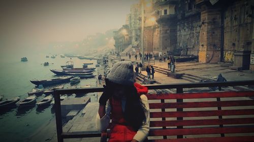 Rear view of woman walking on railing against buildings in city