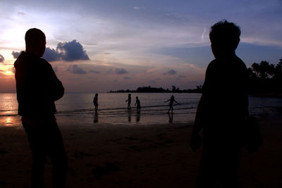 Silhouette of friends standing at sunset