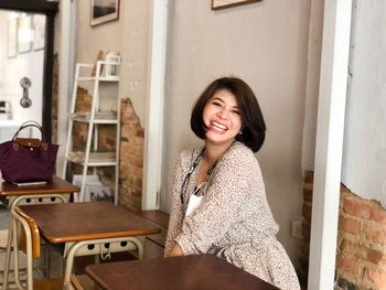 Portrait of smiling young woman sitting on chair at home