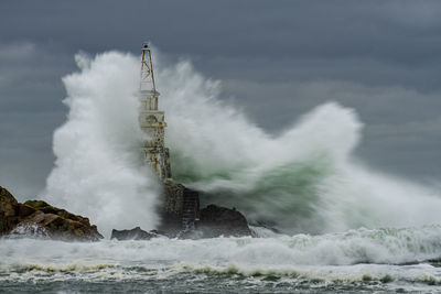 Lighthouse by sea against sky during severe sea storm