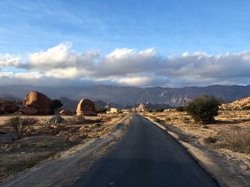 Road leading towards mountains against sky