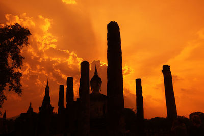 Low angle view of buddha statue and columns against sky during sunset