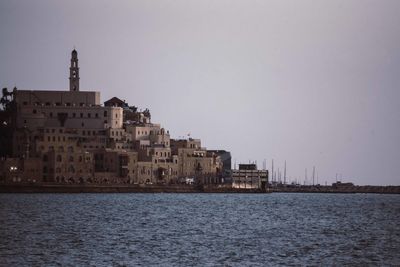 Sea by buildings against clear sky