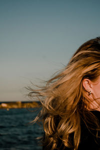 Portrait of waving woman's blonde hair in the wind against sky