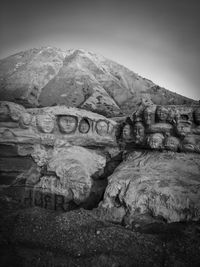 Text on rock formation against sky