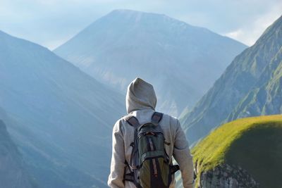 Rear view of man looking at mountains against sky