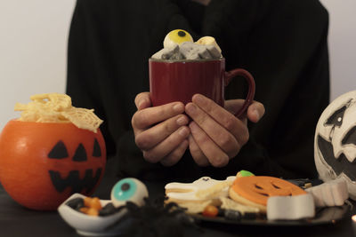 Midsection of woman holding mug with scary halloween drink