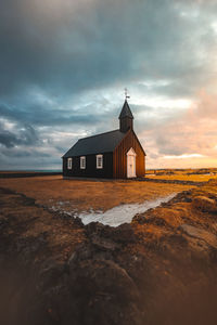 Beach by building against sky during sunset