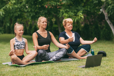 Multi generational family exercising with laptop on grass