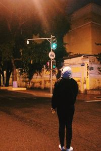 Rear view of man standing on road at night