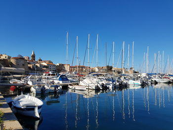 Sailboats moored at harbor against clear blue sky