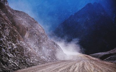 Dust over dirt road amidst rocky mountains