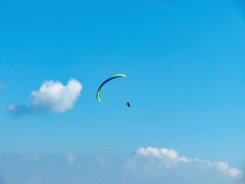 Low angle view of paragliding against blue sky