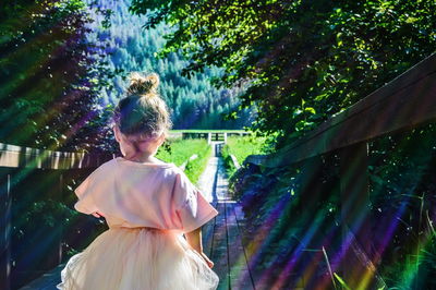 Rear view of baby girl standing on boardwalk in park