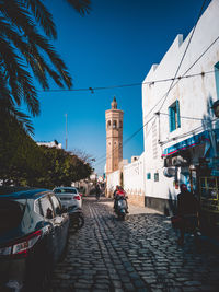 Street amidst buildings in city against blue sky