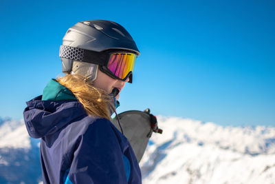 Woman wearing ski goggles and helmet against sky