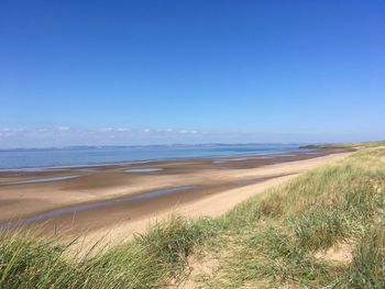 Scenic view of beach against clear blue sky