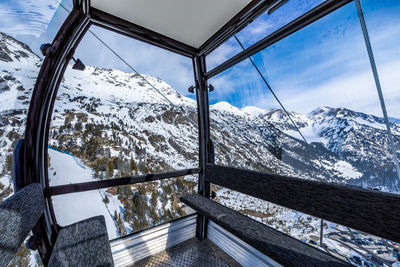 Scenic view of snowcapped mountains against sky seen through window