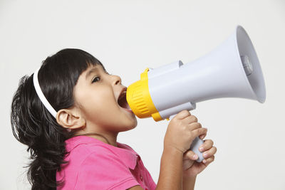 Girl shouting through megaphone against gray background