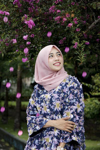 Portrait of a smiling young woman standing against plants