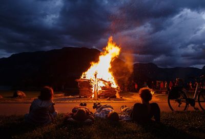 Bonfire on field against cloudy sky at night