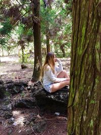 Woman sitting on tree trunk in forest