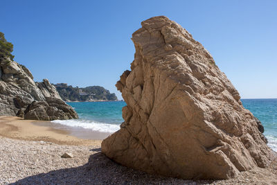 Rock formation on beach against clear sky