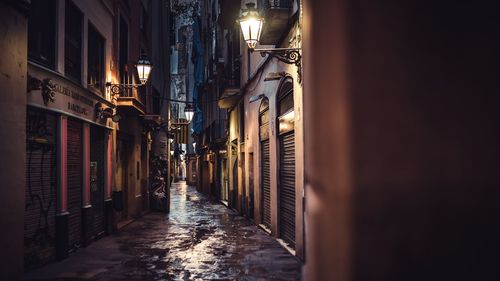 Walkway amidst illuminated buildings against sky