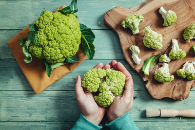 High angle view of hand holding vegetables on table