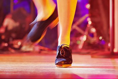 Low section of person dancing on illuminated floor