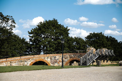 Arch bridge on field against sky