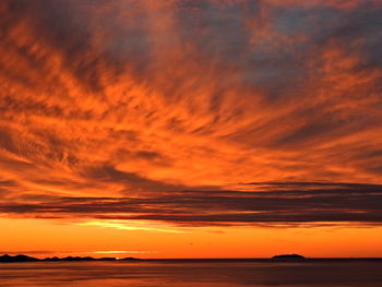 Scenic view of sea against dramatic sky during sunset