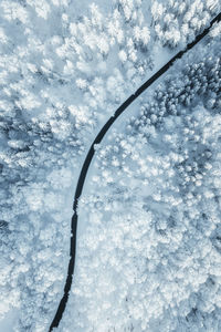 Wintery aerial view at road winding through forest covered in deep snow, austria.